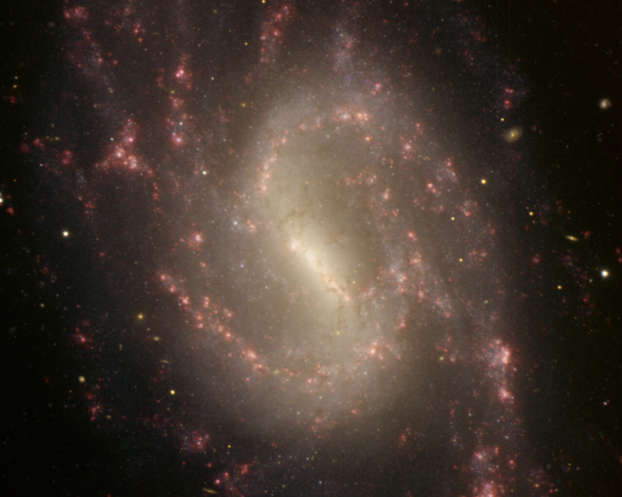 colorful spiral galaxy with pink hues against a black night sky