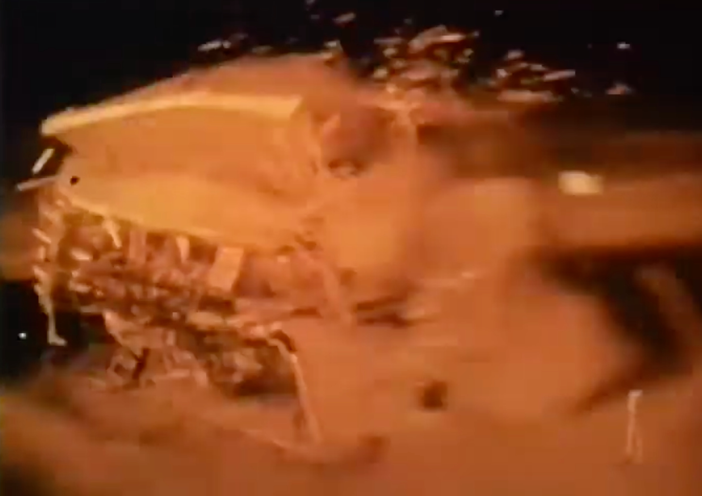 A two-story house is captured in the midst of being violently and completely destroyed by incredible wind force coming from a single direction, the facing wall obliterated, the house interior is revealed as the roof and remaining walls are in the midst of peeling outward and away, pieces of debris are streaking through the air behind the house and in the direction away from the force